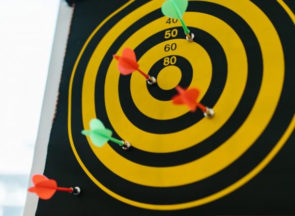 Vibrant darts stuck in a yellow and black dartboard representing precision and strategy.